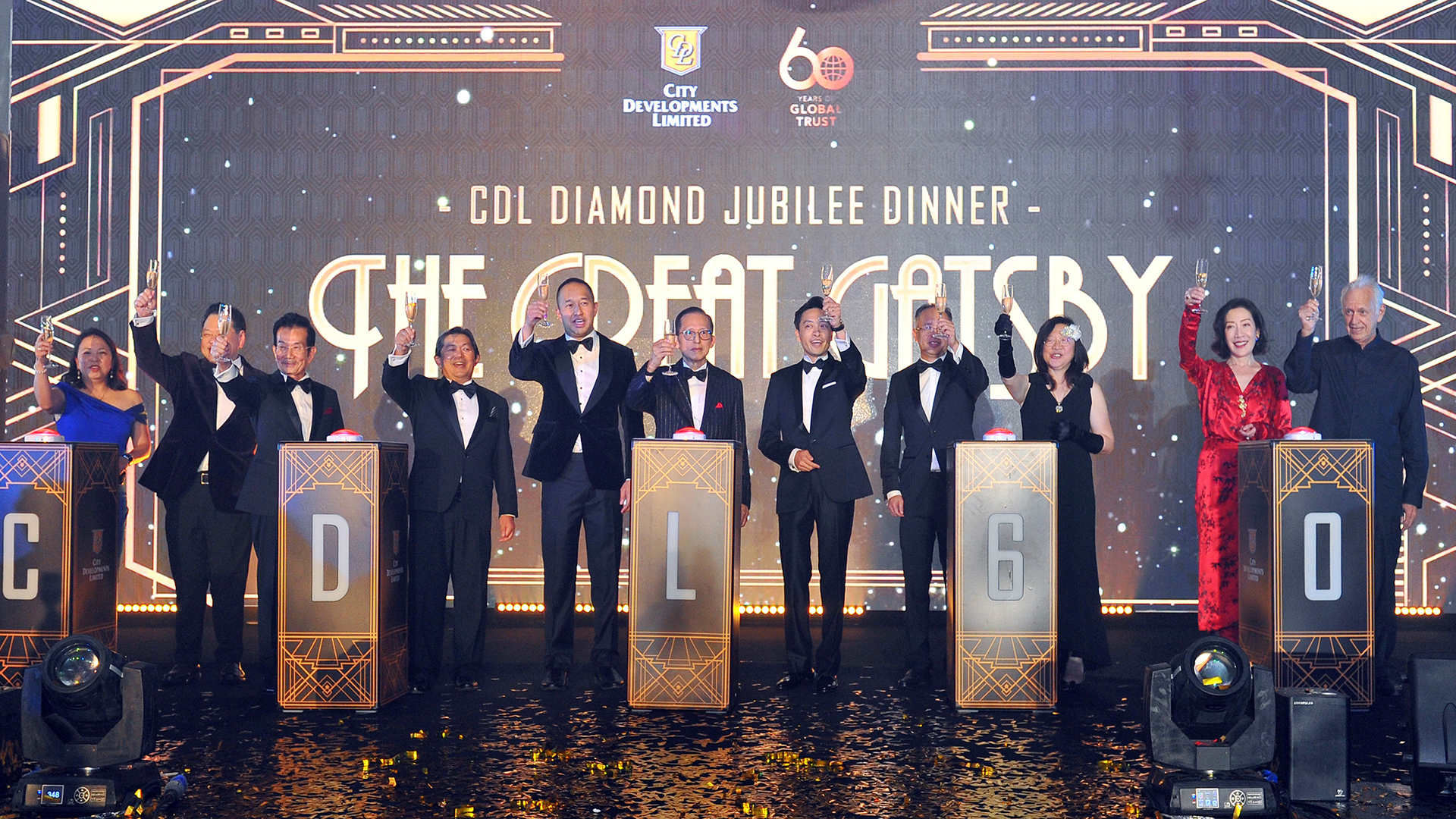 11 CDL executives standing behind a podium, holding a champagne glass and toasting the 60th anniversary of CDL in a Gatsby-themed dinner.