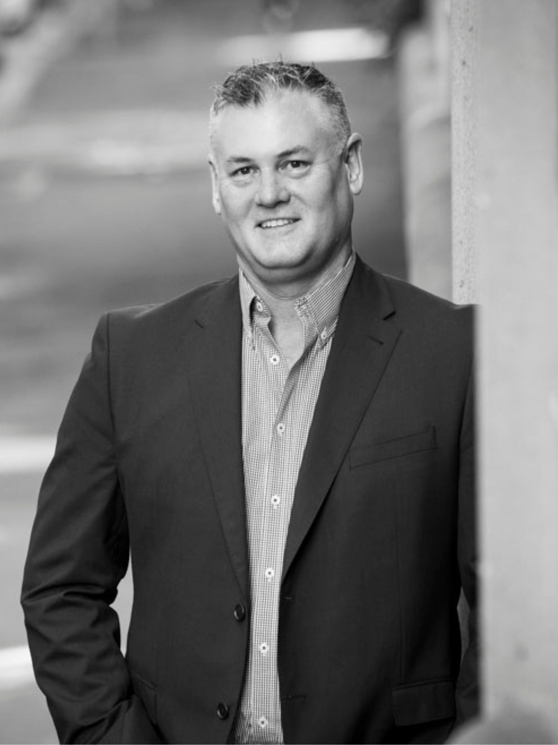 Image of Mark Rabone, CDL Australia's Senior Development Manager, standing next to a concrete wall in black and white.